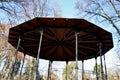 Steel subtle gazebo construction with decorative beams. The roof is wooden in the shape of a flat pyramid. circular dance floor co