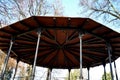 Steel subtle gazebo construction with decorative beams. The roof is wooden in the shape of a flat pyramid. circular dance floor co