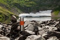 A steel thermos stands on the shore of a mountain lake on a summer day.