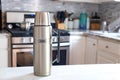 Steel thermos from TERMOS on a white table in the kitchen close-up. Space for text