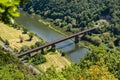 The steel truss structure of the railway bridge seen from above, in the background there are hills overgrown with forest.