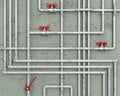 Steel water pipes with red faucets in front of concrete wall,