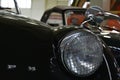 Steel wire grille protected round headlight of Triumph TR3 veteran two seated british sports car, black colour. Royalty Free Stock Photo