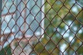 Steel wire net fence with blurred green background Royalty Free Stock Photo