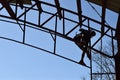 Steel worker welding trusses of a covered gym court.