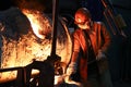 A steelmaker pours pig iron from a blast furnace, sparks and splashes of hot metal fly. Royalty Free Stock Photo