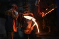 A steelmaker pours pig iron from a blast furnace, sparks and splashes of hot metal fly. Royalty Free Stock Photo