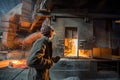 Steelworker at work near arc furnace and pouring liquid metal. Royalty Free Stock Photo
