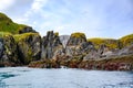 Steep cliffs with moss and algal, caves and seashore in South Georgia Royalty Free Stock Photo