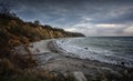 Steep coast with beach, stones and waves under a dark cloudy sky at the Baltic Sea in Mecklenburg-Western Pomerania, Germany, copy