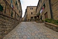 Steep cobblestone street surrounded by vintage stone buildings in Voltera, Tuscany