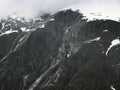 Steep Glacially Polished Cliffs And Mountain Peak Covered With Snow And Clouds, Alaska Royalty Free Stock Photo