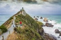 The steep headland of Nugget Point with Nugget Point Lighthouse and rocky islets called The Nuggets at the Catlins, New Zealand.