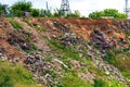 A steep hillside sloping down to the river littered with trash thrown by locals in the village. Slopes in village construction