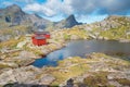 Steep mountains of Lofoten Island on a sunny arctic day. Hermannsdalstinden peak and red cabin of Munkebu hut. Hiking mountains of