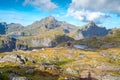 Steep mountains of Lofoten Island on a sunny arctic day. Hermannsdalstinden peak and red wooden cabin of Munkebu hut. Hiking