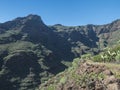 Steep narrow danger hiking trail through Barranco de Guarimiar Gorge. Green mountain canyon slopes with palm trees and