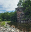 A steep rock overgrown with forest. Bank of mountain river.