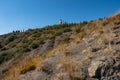 A steep rocky slope with slender cypresses and a lighthouse, Crimea