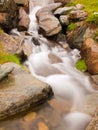 Steep stony stream bed of Alpine brook. Blurred waves of stream running over boulders and stones, high water level after rains Royalty Free Stock Photo