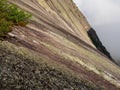 Steep textured granite mountain slope. Stone texture. Cross section of rocks. Geological layers. Colored layers of stones in Royalty Free Stock Photo