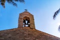 Steeple on top of roof of christian orthodox byzantine Greek church. Big bronze bell, and a big white cross, background view of Royalty Free Stock Photo