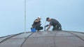 The steeplejacks are working with injector with building material at the roof