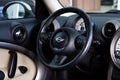 Steering wheel of chrome and leather details in the interior design of a luxurious black and beige car mini Cooper against the