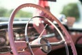 The steering wheel of a pink classic car