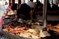 A steet food stall where a wide variety of tasty sausage portions, big slices of pork and beef meat and meat loafs are roasting on