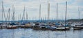 Many small sailing boats with masts without rigging anchor at a landing stage in the harbour of the big lake