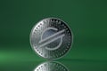 Stellar XLM Crypto coin placed on reflective surface and lit with the green light