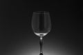 Stem and bowl of an empty crystal goblet on a backlit black background, in low key.