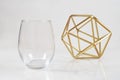 Stemless wineglass mockup with contemporary abstract gold sculpture