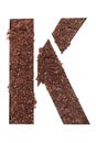 Stencil letter K made above dirt on white surface