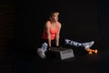 Step aerobics on a dark background stands in his hands with dumbbells in bright clothes, on the platform orange Royalty Free Stock Photo