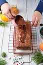 Step-by-step decoration of a carrot cake with chocolate glaze, ganache and candied fruits in a Christmas style on a light wooden Royalty Free Stock Photo