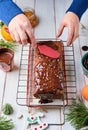 Step-by-step decoration of a carrot cake with chocolate glaze, ganache and candied fruits in a Christmas style on a light wooden Royalty Free Stock Photo