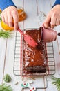 Step-by-step decoration of a carrot cake with chocolate glaze, ganache and candied fruits in a Christmas style on a light wooden Royalty Free Stock Photo