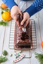 Step-by-step decoration of a carrot cake with chocolate glaze, ganache and candied fruits in a Christmas style on a light wooden Royalty Free Stock Photo