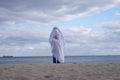 Ghost at seashore holding pumpkin on halloween