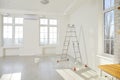 Step ladder and paint bucket standing in empty room in new house with freshly painted white walls. Royalty Free Stock Photo