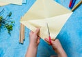 Step-by-step making of a paper weather vane by a child on a blue concrete background. Children`s creativity, divas, crafts