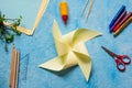 Step-by-step making of a paper weather vane by a child on a blue concrete background. Children`s creativity, divas, crafts