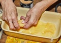 Step-by-step recipe of potato gratin. Hands stack potato slices to glass baking dish. Potato casserole