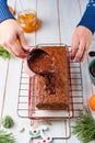 Step-by-step decoration of a carrot cake with chocolate glaze, ganache and candied fruits in a Christmas style on a light wooden Royalty Free Stock Photo