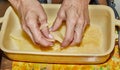 Step-by-step recipe of potato gratin. Hands stack potato slices to glass baking dish. Potato casserole