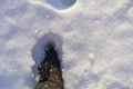 Step with your foot in a warm black boot in deep snow in winter