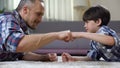 Stepfather and child fist bumping, partnership greeting, happy childhood moment