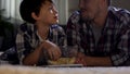 Stepfather and son watching TV at home until late and eat junk food, closeness